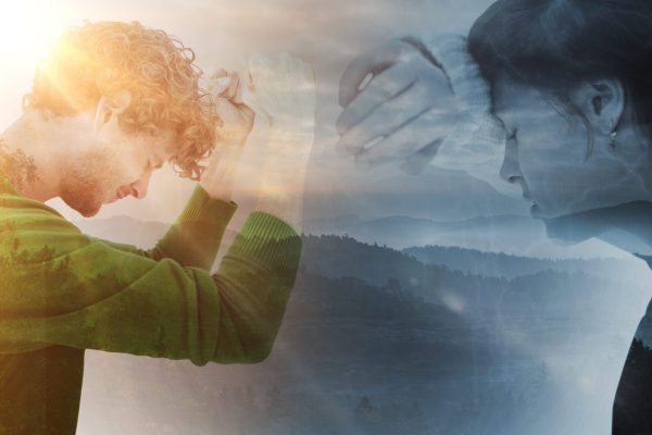 Sad pretty brunette leaning against wall against trees and mountain range against cloudy sky