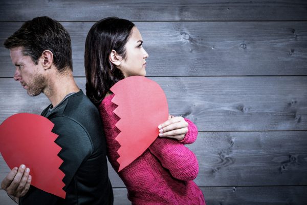 Serious couple standing back to back  against bleached wooden planks background